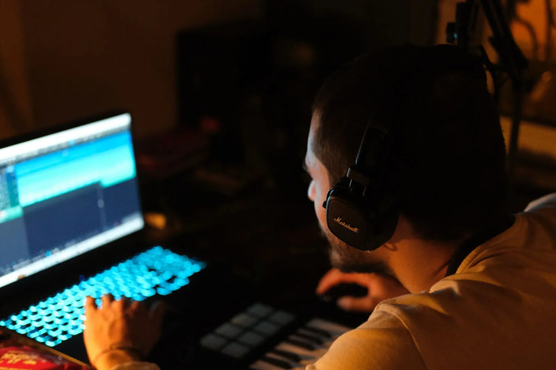 Artiste qui cherche une instrumentale en ligne, casque sur les oreilles devant son ordinateur