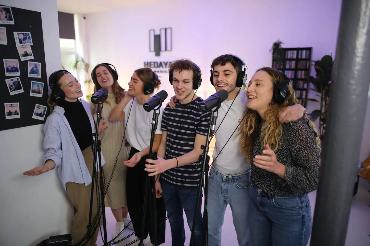 Six collaborateurs chantent ensemble devant des micros pendant un team building musical au studio Hedayat Music